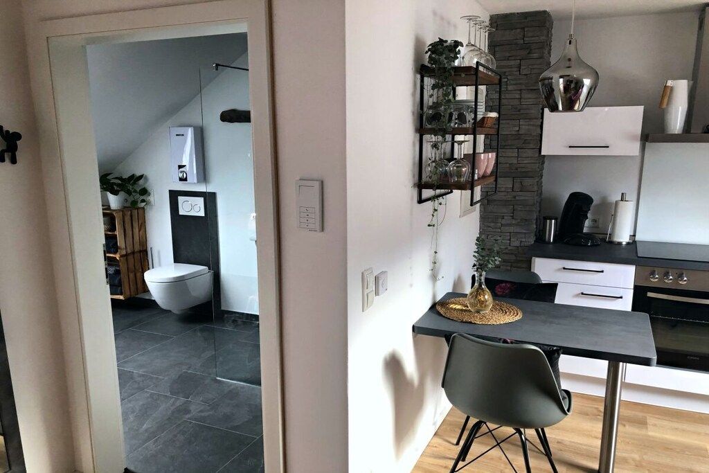 Una cucina moderna con un piano di lavoro nero, una sedia grigia e una lampada a sospensione.