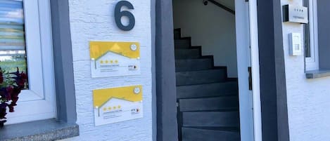 A building entrance with a number '6' sign, a staircase, and two yellow plaques with text and a star rating.