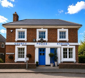 A two-story brick building with a blue door and windows, labeled 'COUNTY POLICE STATION.' - Historic Charm in the Heart of Fordingbridge (Fordingbridge)