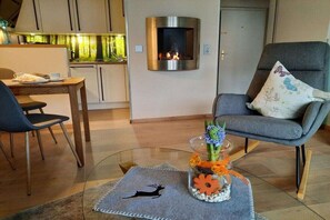 A modern living room with a fireplace, a dining area, and a comfortable seating arrangement. - Holiday apartment with 1 bedroom (Hahnenklee)