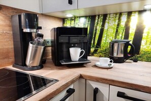 A modern kitchen with a coffee machine, a kettle, and a cup on the counter. - Holiday apartment with 1 bedroom (Hahnenklee)