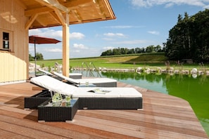 Eine Holzterrasse mit Liegestühlen und einem kleinen Pool.