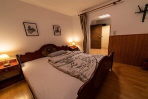 A bedroom with a wooden bed, bedside lamps, and a wooden wardrobe. - Monika House in Übersee am Chiemsee (Übersee)