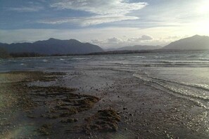 A beach with waves, distant mountains, and a clear sky. - Monika House in Übersee am Chiemsee (Übersee)