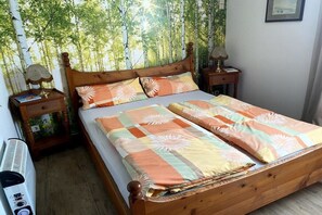 A bedroom with a wooden bed, two bedside tables, and a wall mural. - Monika House in Übersee am Chiemsee (Übersee)