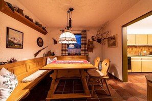A cozy dining area with a wooden table, benches, and a hanging lamp. - Monika House in Übersee am Chiemsee (Übersee)