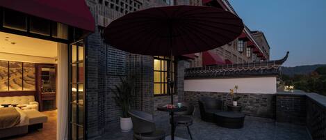 An outdoor seating area with a table and chairs, a potted plant, and a large umbrella.