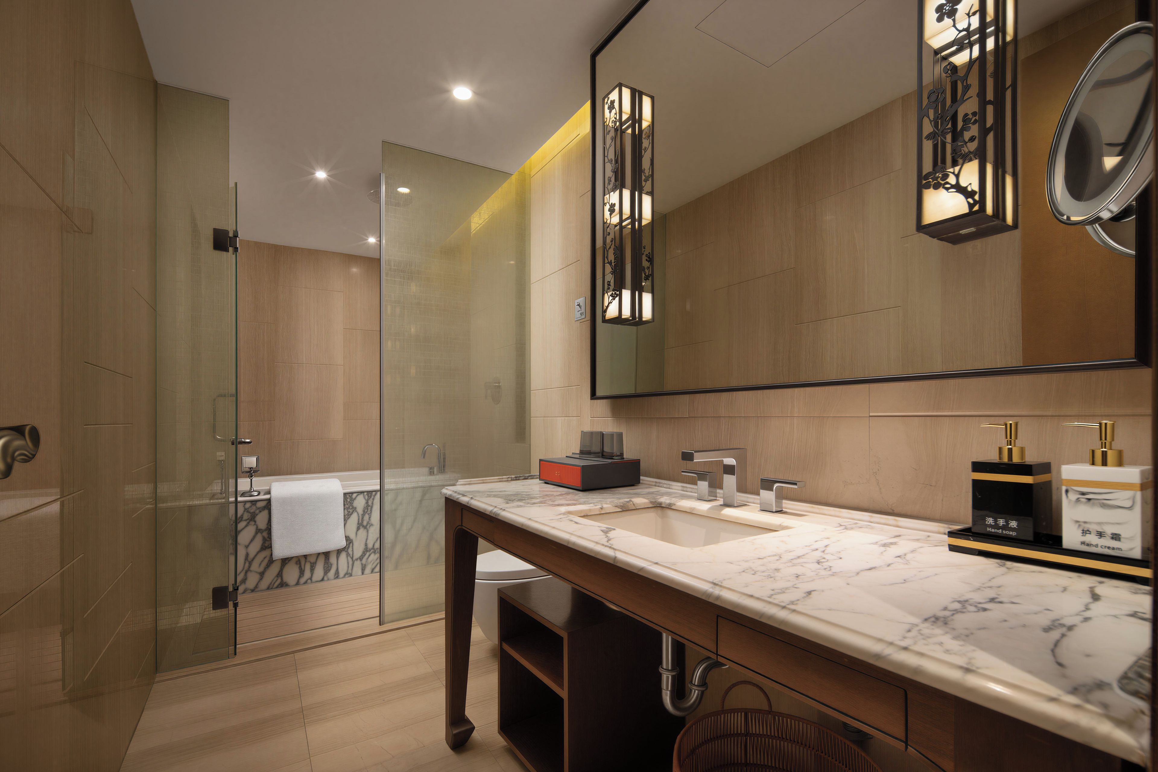 A modern bathroom with a glass-enclosed shower, a marble sink, and a large mirror.