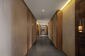 A hotel corridor with doors on both sides, recessed lighting, and a tiled floor. - Yijiangchunshui 1912 Guofeng Hotel (Hangzhou)