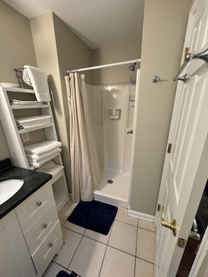 Un baño con ducha, lavabo y toallero.