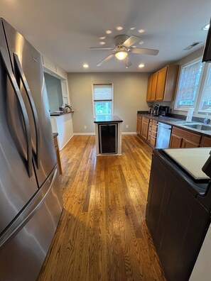 Une cuisine équipée d’un réfrigérateur, d’un lave-vaisselle, d’un plancher en bois et d’un ventilateur de plafond.