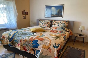 Ein Bett mit einer Blumensteck, einer Nachttischlampe und einem gerahmten Bild an der Wand.