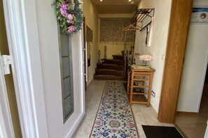 Ein Flur mit einem gemusterten Teppich, einer hölzernen Bank und einer Treppe.