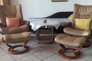 A living room with two leather armchairs, a small wooden table, and a sofa. - Holiday apartment with 2 bedrooms (Wölpinghausen)