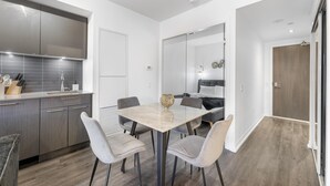 Uma cozinha moderna com armários cinza, uma mesa de jantar com quatro cadeiras e um pequeno vaso decorativo.