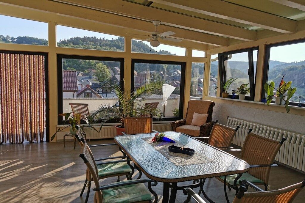 A sunlit room with a table, chairs, and potted plants.