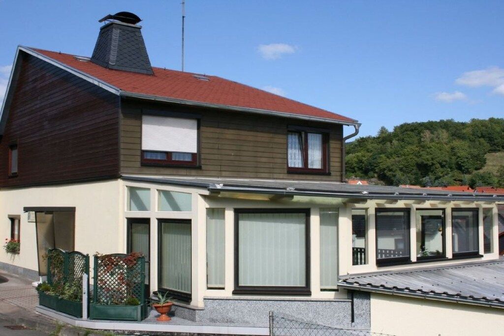 Una casa de dos pisos con un porche cubierto y una chimenea.