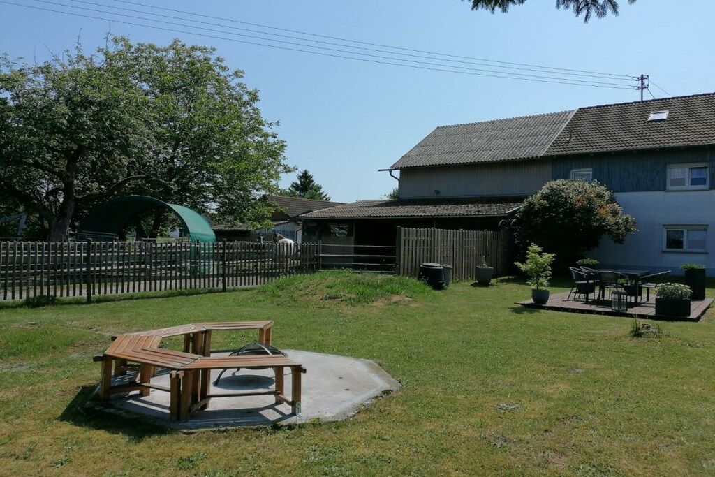 A residential area with a fenced yard, a wooden bench, and a house with a tiled roof.