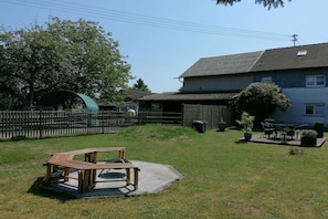 A residential area with a fenced yard, a wooden bench, and a house with a tiled roof. - Melitta holiday apartment (Heiligenberg)