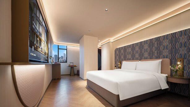 A modern hotel room with a large bed, a desk, and a view of the cityscape. - Manxin Hotel Wuhan Hankou xinhua Road (Wuhan)