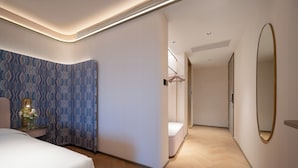 A hotel room with a bed, a bedside table with a vase of flowers, a wall-mounted mirror, and a walk-in closet. - Manxin Hotel Wuhan Hankou xinhua Road (Wuhan)