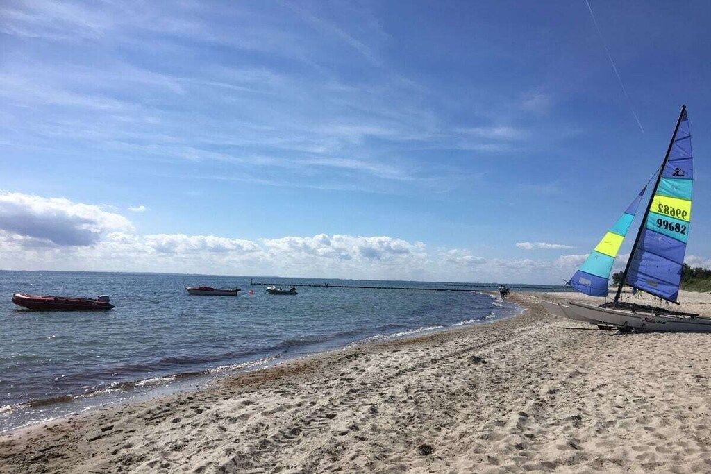 A beach with a sailboat and a pier in the background.