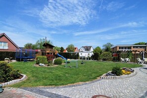 A residential area with a well-maintained lawn, a children's play area, and a paved walkway. - Type 2 in the Schwardt house (Kellenhusen)
