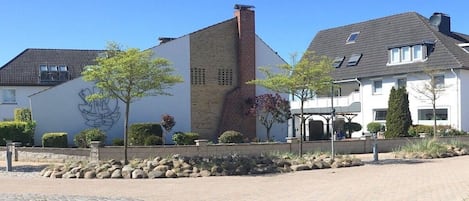 A residential building with a brick facade, a stone pathway, and a landscaped garden.