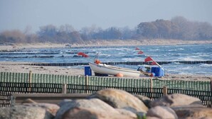 Une plage bordée d’une rangée de bateaux et d’une clôture en bois.