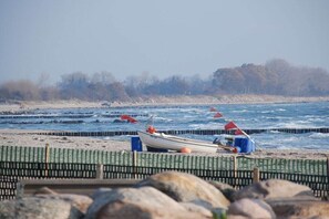 Een strand met een rij boten en een houten omheining.