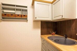 A kitchen with a wooden countertop, a sink, and a cabinet above the counter. - Apple tree Lenzkirch (Lenzkirch)