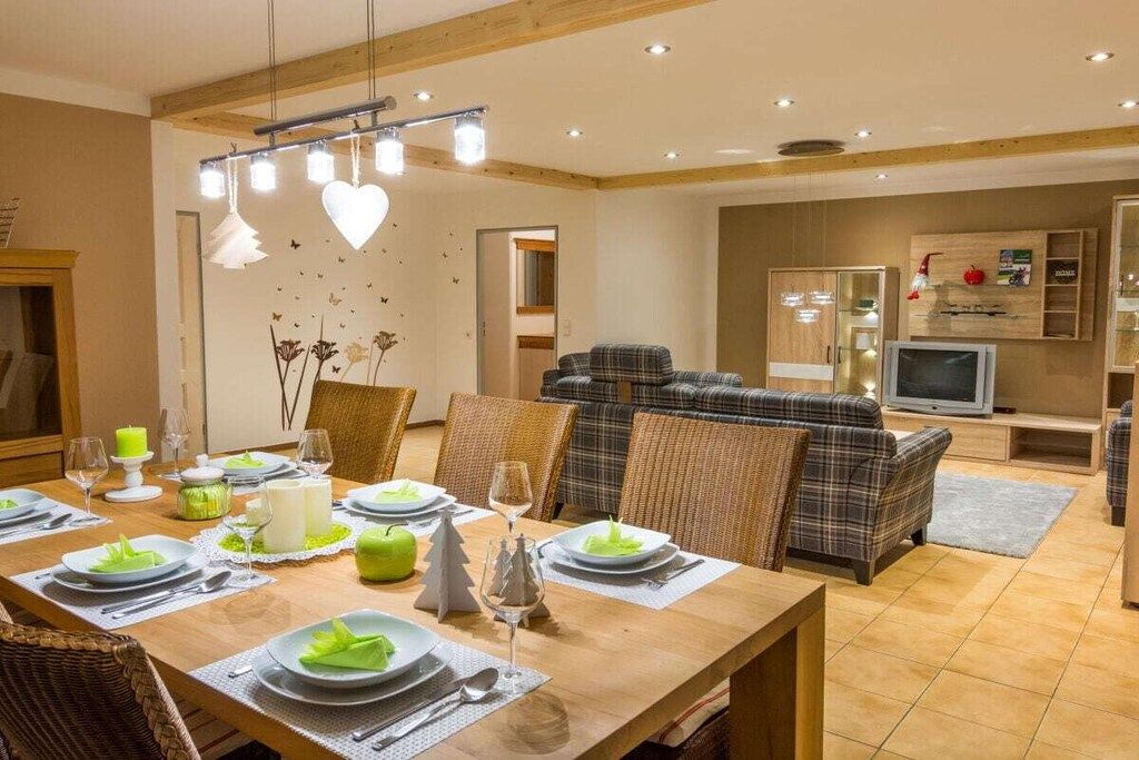 Een eetgedeelte met een houten tafel, gedekt voor een maaltijd, met aan weerszijden rieten stoelen.
