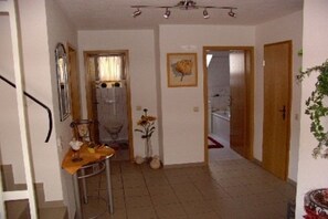 A hallway with a wooden door, a mirror, a small table with a vase, and a framed picture on the wall. - Holiday apartment with 3 bedrooms (Wehr-Öflingen)