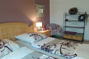 A bedroom with a wooden headboard, a nightstand with a lamp, a chair, and a metal shelf with decorative items. - Holiday apartment with 3 bedrooms (Wehr-Öflingen)