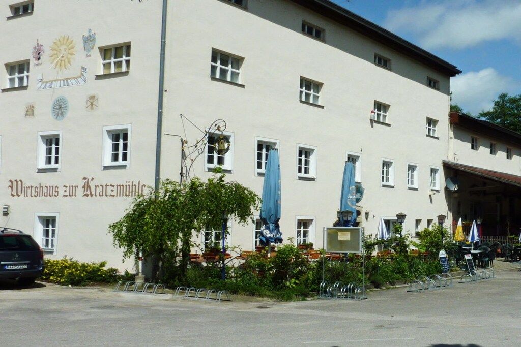 A building with a sign reading 'Wirtshaus zur Kratzmühle' and a statue in front.