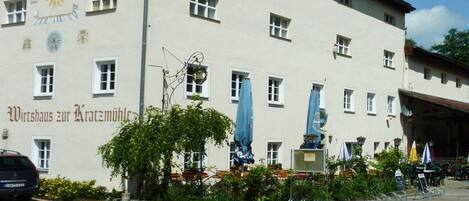 A building with a sign reading 'Wirtshaus zur Kratzmühle' and a statue in front.