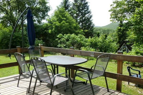 Une terrasse avec une table et des chaises, offrant une vue sur un paysage verdoyant et luxuriant, avec des arbres et des collines.