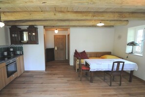 A compact kitchen with wooden cabinets and a dining area with a table and chairs. - Holiday home with 2 bedrooms (Wunstorf-Idensen)