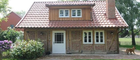 A brick house with a tiled roof, a front door, and a small porch.