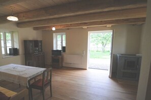 A room with wooden flooring, a dining table with chairs, a fireplace, and a television on a cabinet. - Holiday home with 2 bedrooms (Wunstorf-Idensen)