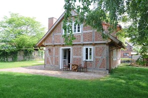 Una casa de maó amb un porxo, una porta i una taula petita amb caires.