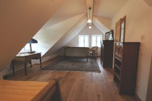 A sloped ceiling attic room with a wooden floor, a radiator, a desk, a chair, and a cabinet. - Holiday home with 2 bedrooms (Wunstorf-Idensen)