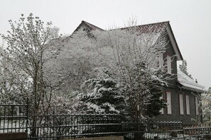 A building with a sloped roof, surrounded by snow-covered trees and a metal fence. - ||--------------------------Old lodging house-----------------------|| (Wernigerode)