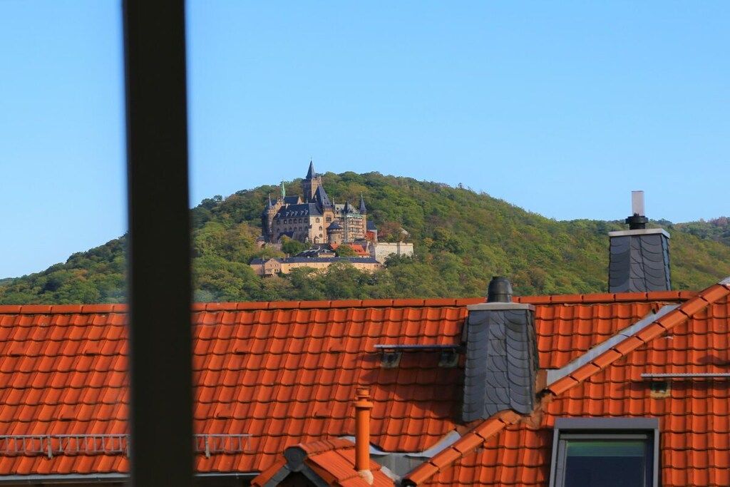 Eine Burg auf einem Hügel mit einem roten Ziegeldach im Vordergrund.