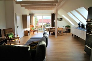 A spacious living area with a sofa, chairs, a dining table, and a kitchen area with a stove. - ||--------------------------Old lodging house-----------------------|| (Wernigerode)