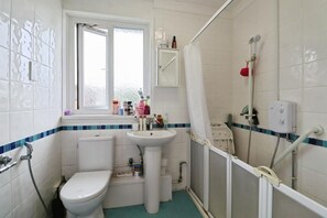 Ein Badezimmer mit Toilette, Waschbecken, Dusche und einem Fenster.