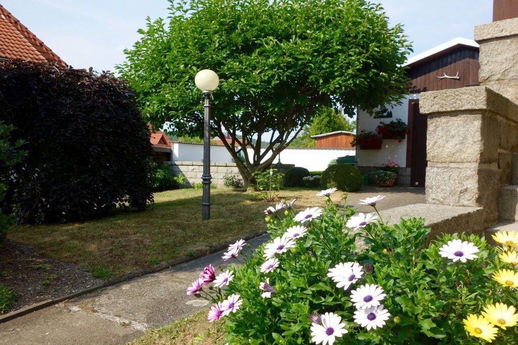 A residential area with a paved pathway, a street lamp, and a variety of flowering plants.