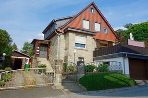 A two-story house with a stone facade, a red-tiled roof, and a gated driveway. - House "Brockenblick 1" (Wernigerode)