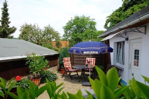 An outdoor patio with a table and chairs, a blue umbrella, and potted plants. - House "Brockenblick 1" (Wernigerode)