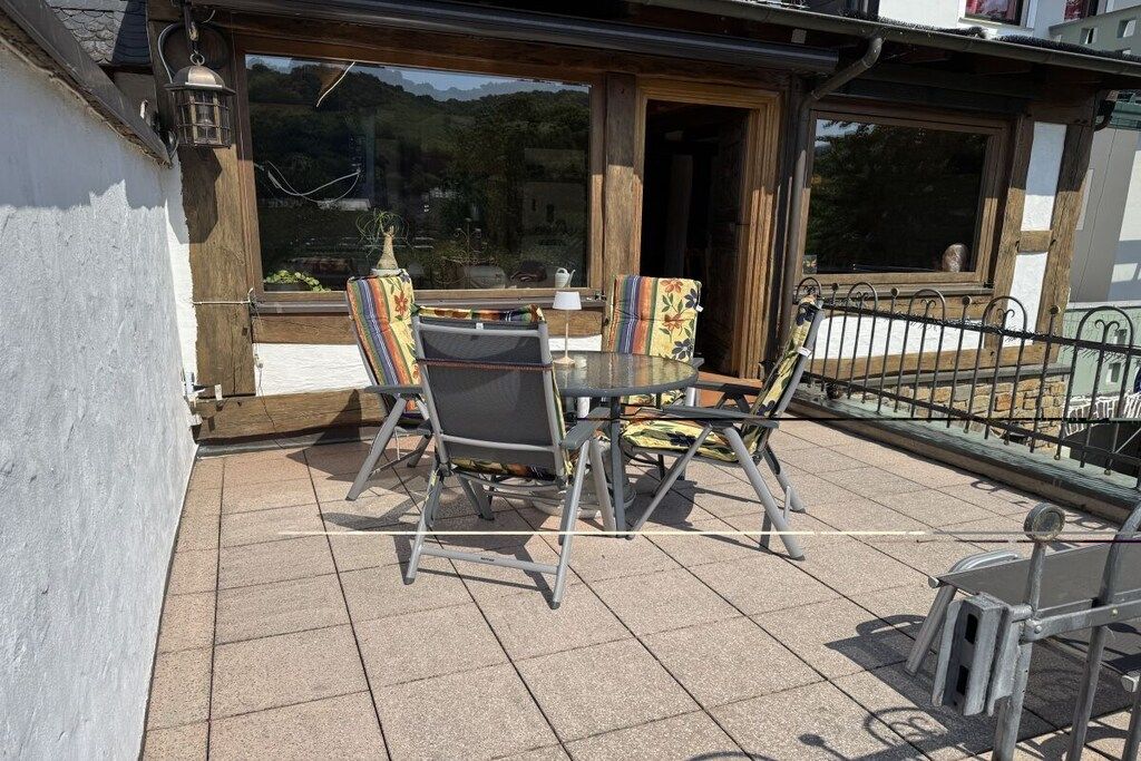 An outdoor patio with a table and chairs, a lamp, and a view of the surrounding landscape.